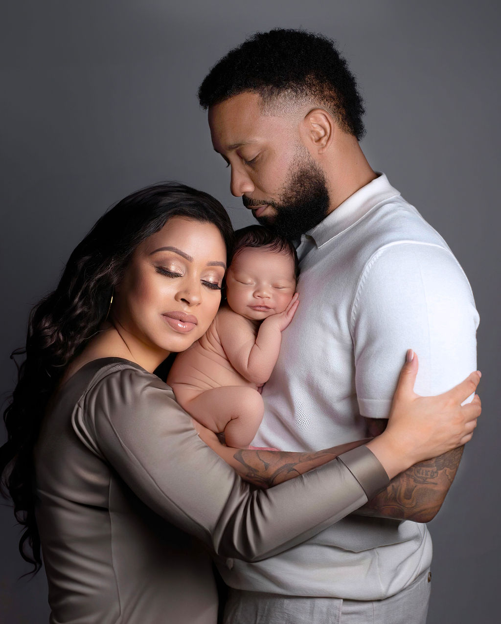 A San Antonio family of three holds their newborn son in studio against a neutral backdrop.